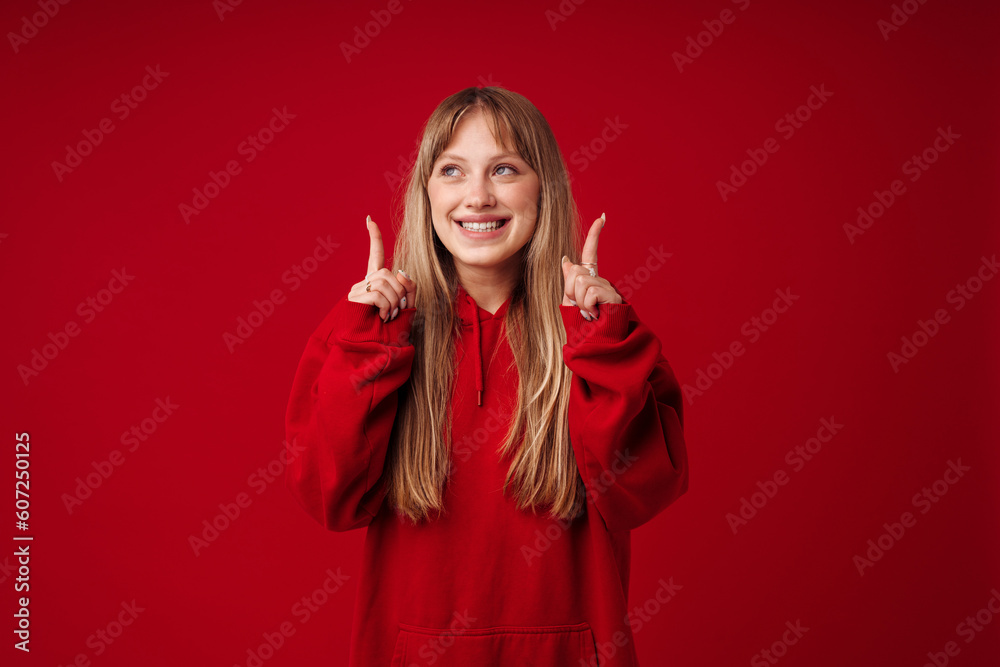 Young blonde woman smiling and pointing fingers upward