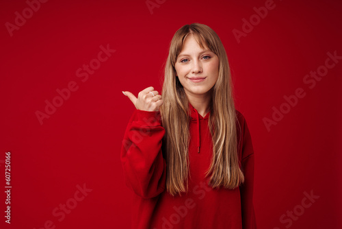Young blonde woman smiling and pointing finger aside