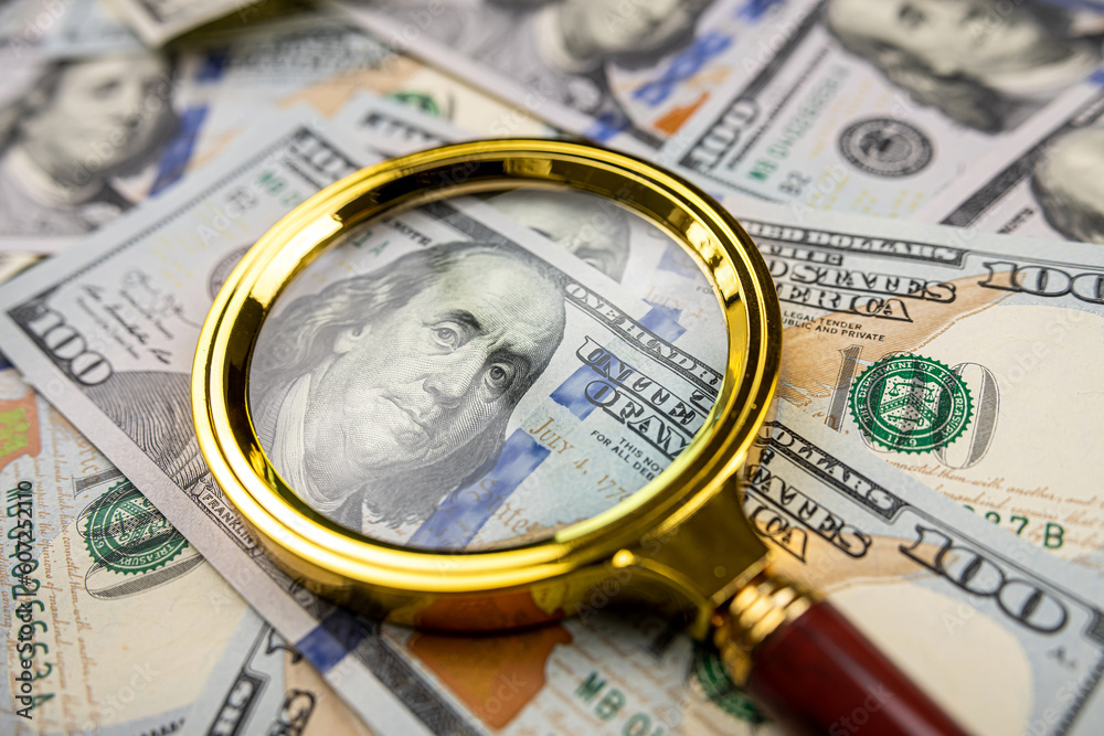 Golen magnifying glass on different dollars money as financial background Golen magnifying glass on different dollars money as financial background