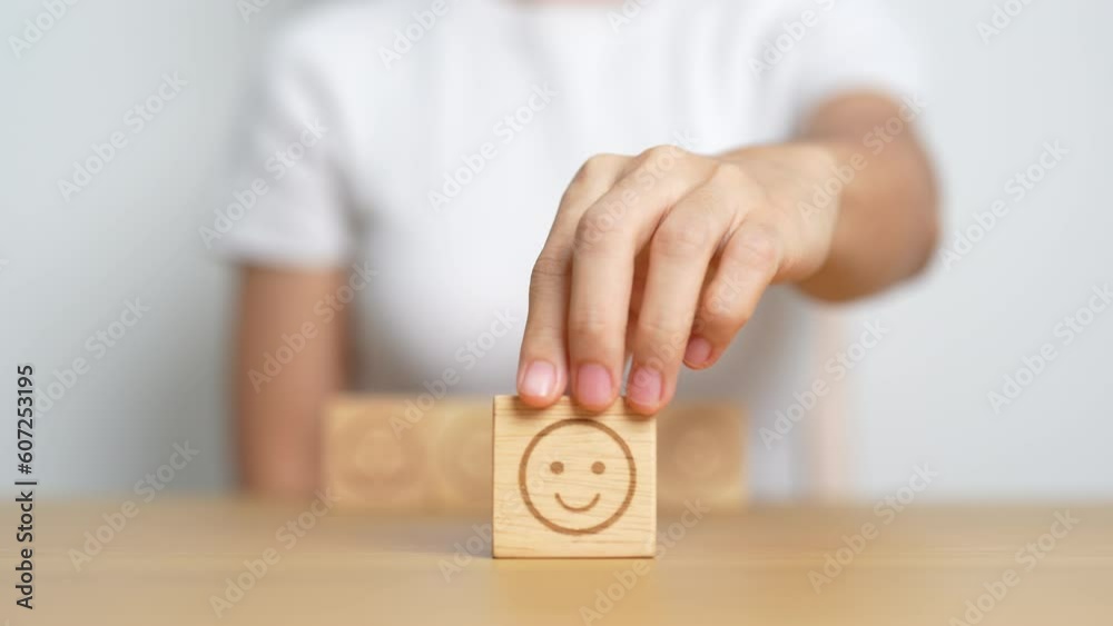 Hand choosing happy face from Emotion block for customer review, good experience, positive feedback, satisfaction, survey, evaluation, assessment, mood and world mental health day concept