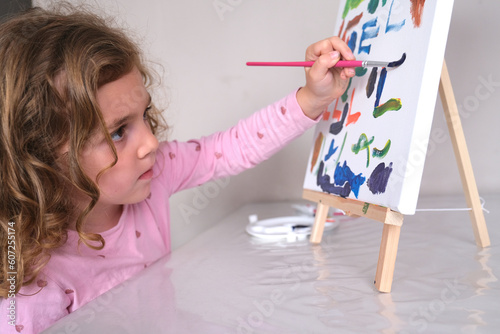 relaxed little girl painting on a canvas with acrylic paint