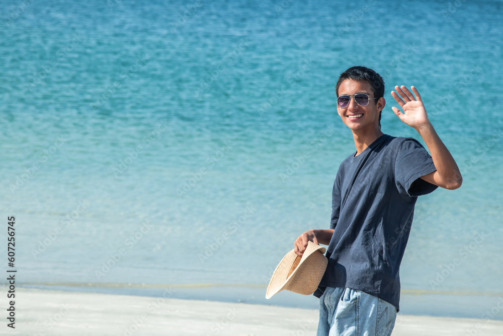 young latin hispanic man with hat on the beach waving hand young latin hispanic man with hat on the beach waving hand
