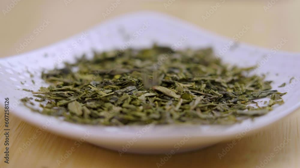 Japanese green sencha tea dried leaves closeup falling in slow motion