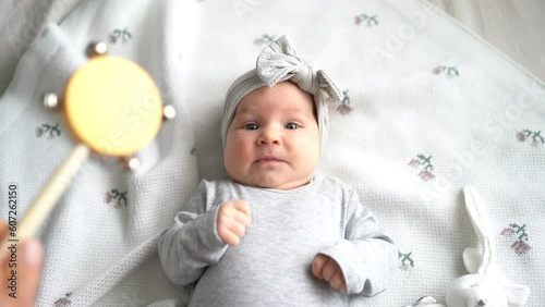 Young dad and baby daughter playing with rattle toy. New father nursing little two month child at home. Baby care and parenthood concept