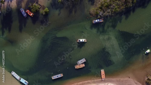 Rising rotating aerial drone bird's eye top view of the tropical Catu river with many small wooden ferries used to transport people and cars in the village of Sibauma, Rio Grande do Norte, Brazil photo