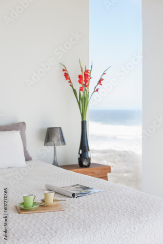 Breakfast tray on bed in modern bedroom with ocean view