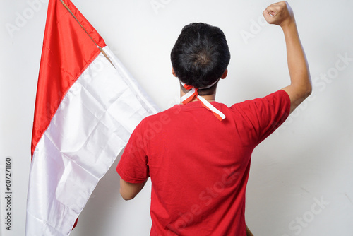Excited young Asian man holding Indonesian flag while celebrating Indonesia Independence day photo