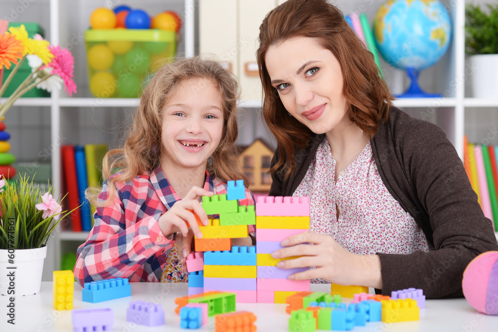 Fototapeta premium Cute little girl and her mother playing colorful plastic blocks