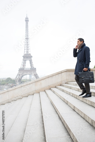 Businessman talking on cell phone on steps near Eiffel Tower, Paris, France
