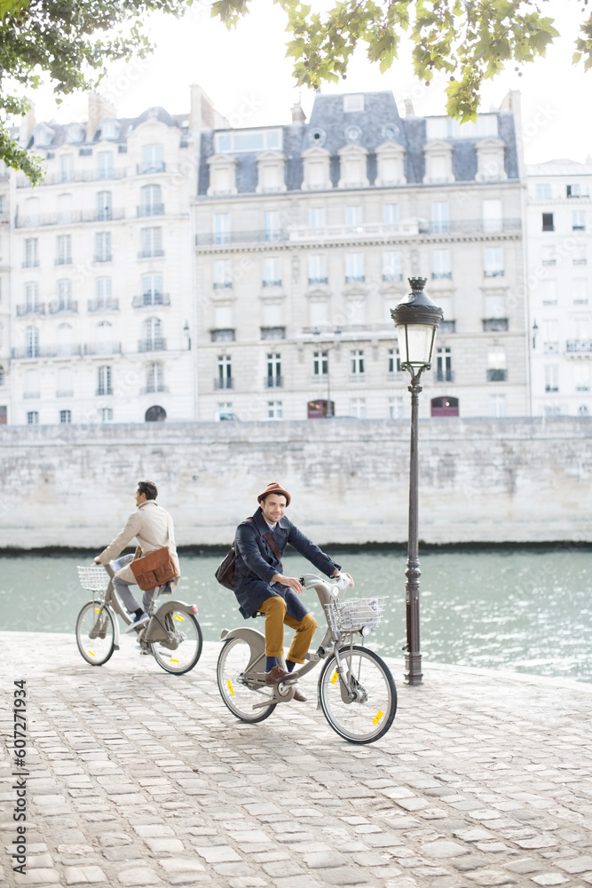 Men riding bicycles along Seine River, Paris, France