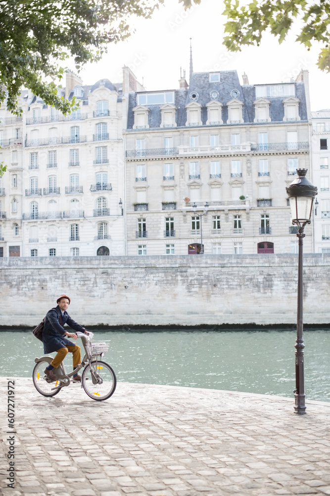 Man riding bicycle along Seine River, Paris, France