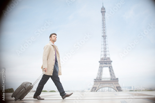 Businessman pulling suitcase near Eiffel Tower, Paris, France