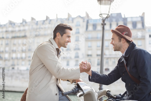 Canvas Print Businessmen shaking hands on bicycles along Seine River, Paris, France