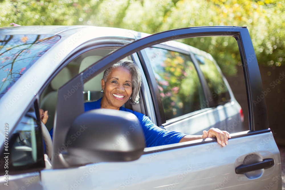 Portrait of confident senior woman getting out of car