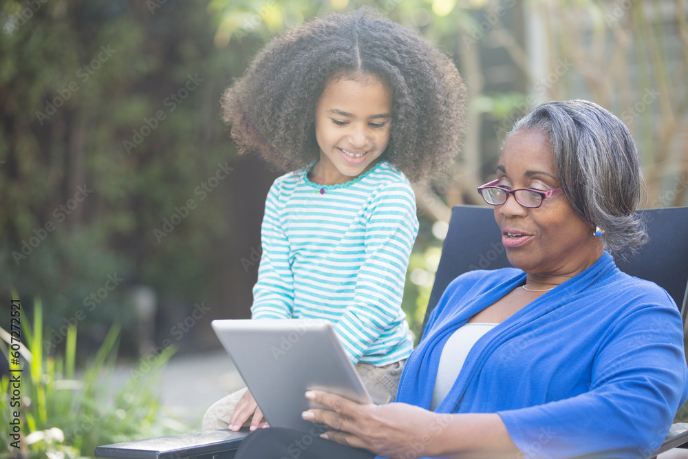 Grandmother and granddaughter using digital tablet outdoors Grandmother and granddaughter using digital tablet outdoors