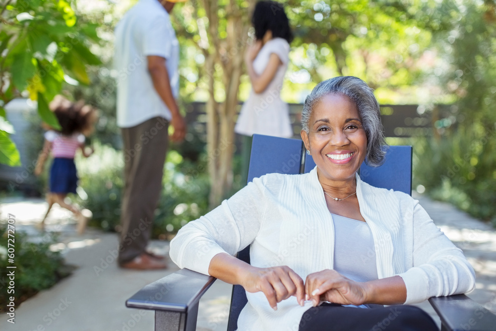 Portrait of smiling senior woman on patio with family in background