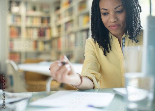 Businesswoman with paperwork at laptop