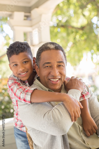 Close up portrait of smiling grandfather and grandson hugging on porch