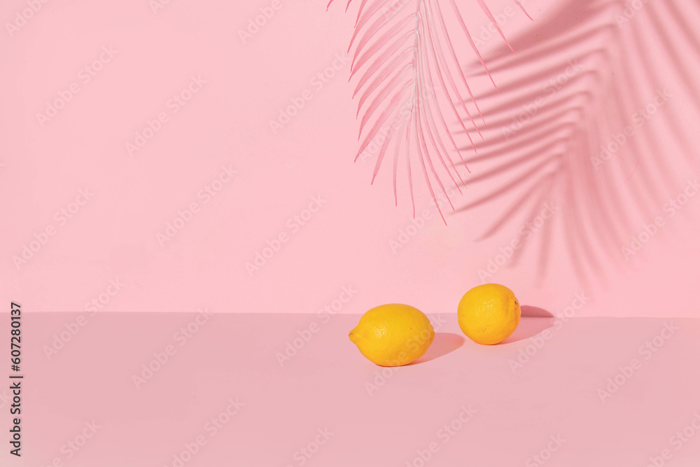 Summer creative layout with lemons and palm tree shadow on pink ...