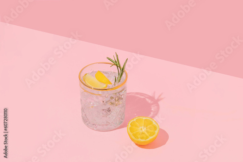 Summer creative layout with coctail glass and lemon half on pink background. 80s or 90s retro aesthetic idea. Minimal summer coctail idea.