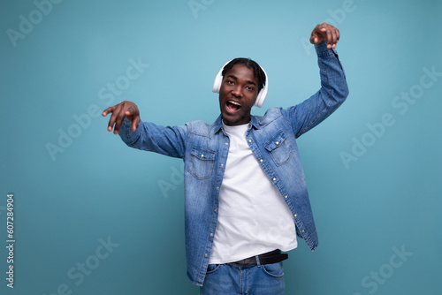 cool dude american man with dreadlocks in a denim jacket relaxes to music in headphones