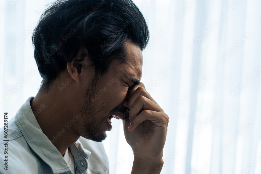 Asian young upset depressed man sitting alone in living room at home. Asian young upset depressed man sitting alone in living room at home.