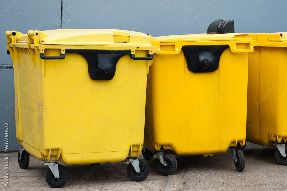 yellow garbage containers on a gray background close-up yellow garbage containers on a gray background close-up