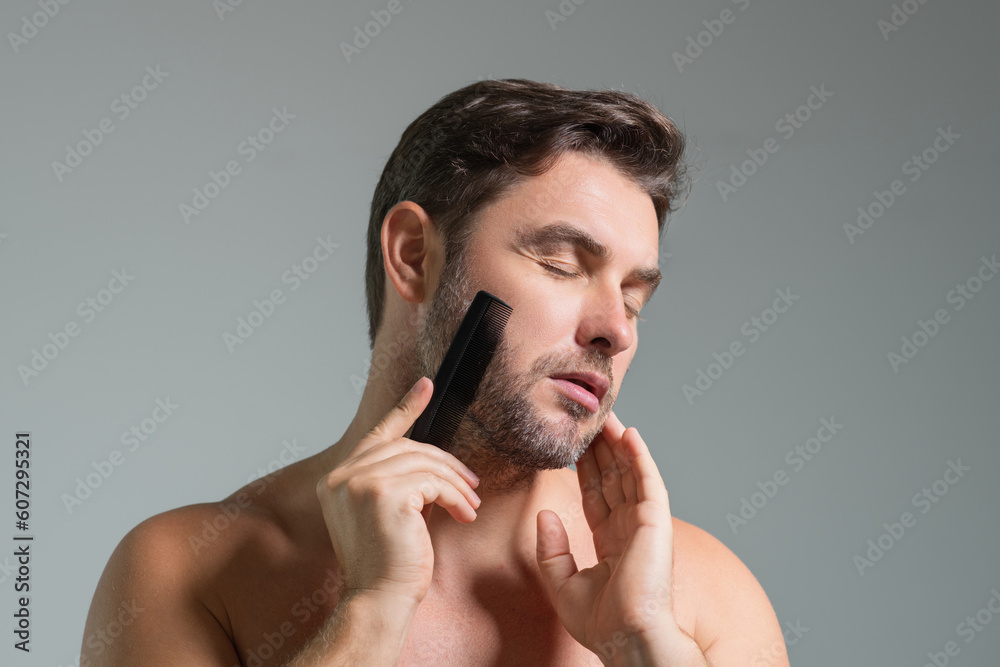 Obraz premium Caucasian man trying to make a beard hair comb by himself with comb. Male haircut. Male haircut. Carber shop. Barber comb. Combing beard hair concept. Mens hair style and hair comb.