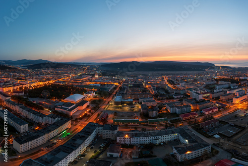 Morning aerial photograph of the city. Top view of buildings and empty streets. Dawn. Morning twilight. Hills in the distance. City of Magadan, Magadan region, Siberia, Far East of Russia.