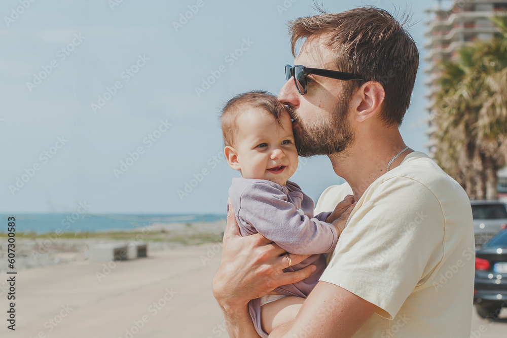 close-up portrait of dad and little cute daughter 8 months old on the seashore in summer on a sunny day, the concept of paternity and father's day holiday close-up portrait of dad and little cute daughter 8 months old on the seashore in summer on a sunny day, the concept of paternity and father's day holiday