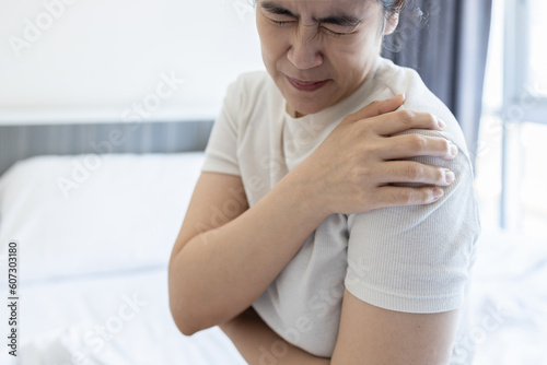 Asian middle aged woman suffering from shoulder pain,shoulder dislocation,aching numbness and weakness,tired female patient with Dislocated shoulder joint,discomfort caused by illness or injury