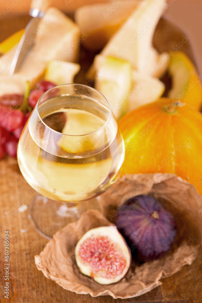 Cheese plate served with grapes, melon, figs, crackers, honey, nuts and white wine on a wooden table Cheese plate served with grapes, melon, figs, crackers, honey, nuts and white wine on a wooden table