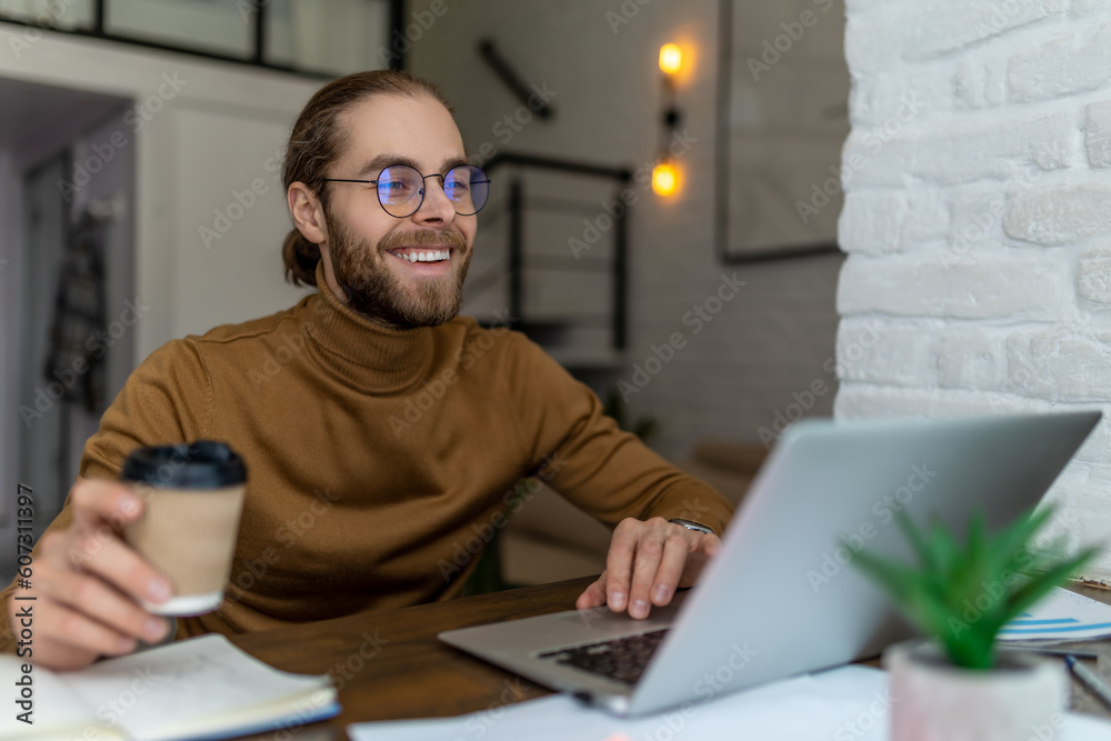 Bearded man freelancer in glasses working at home or in cafe with laptop. Bearded man freelancer in glasses working at home or in cafe with laptop.