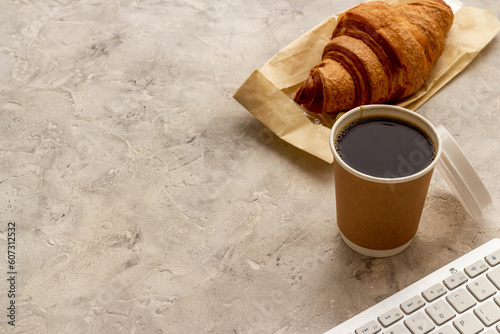 One disposible paper cup of coffee to go with croissant photo