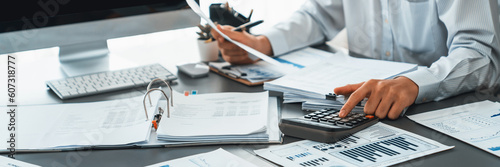 Fotografie Corporate auditor calculating budget with calculator on his office desk
