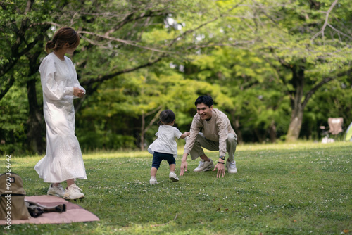 新緑の公園でお父さんの方に走っていく女の子