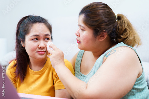 Unhappy - sad Asian woman crying and her friend try to embracing and consoling with empathy.