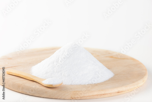 Pile of glucose or grape sugar in a spoon on a wooden board, white background. photo