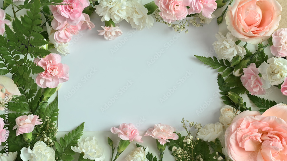 Frame made of pink rose, carnation and fern leaves on white background. Flat lay, top view with space for text