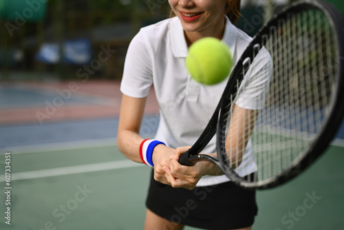 Young sporty woman tennis player hitting ball with a racket during match. Fitness, sport, exercise concept © Prathankarnpap