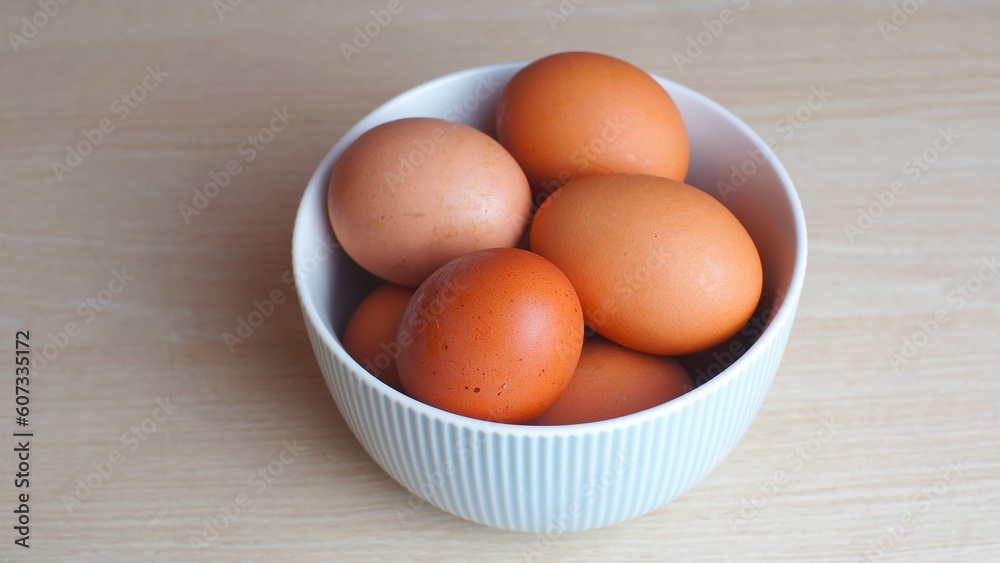 Fresh eggs in ceramic bowl on wooden table as a background with copy space Fresh eggs in ceramic bowl on wooden table as a background with copy space