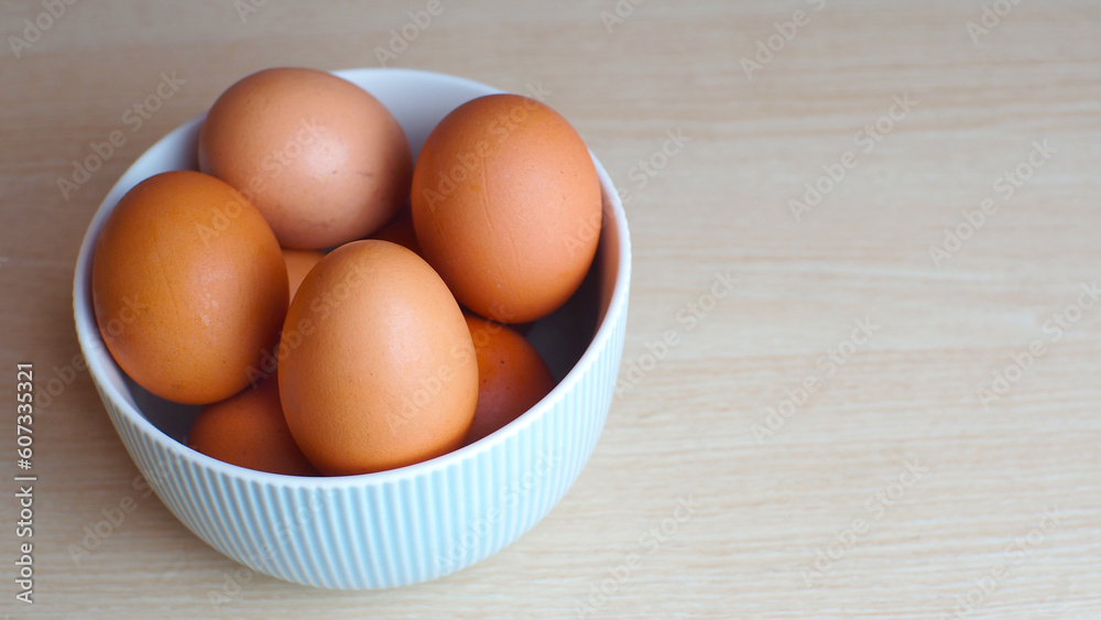 Fresh eggs in ceramic bowl on wooden table as a background with copy space Fresh eggs in ceramic bowl on wooden table as a background with copy space