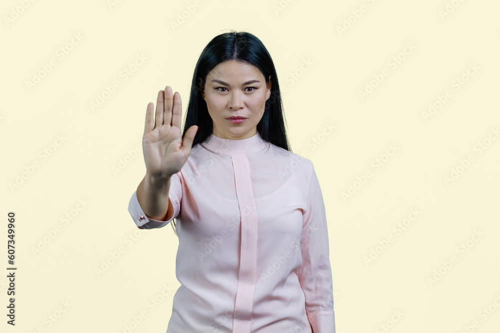 Young asian woman is showing stop gesture by her hand. Palm saying no to you. Isolated on white. Young asian woman is showing stop gesture by her hand. Palm saying no to you. Isolated on white.