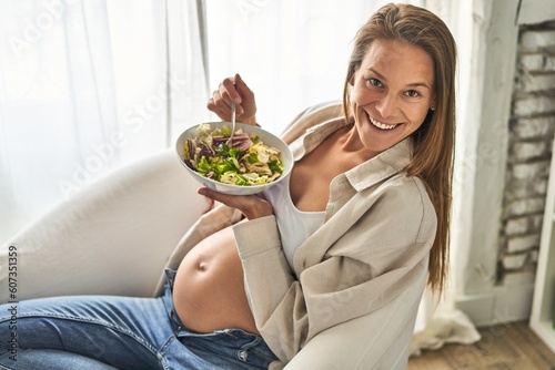 Pregnant woman savors salad in serene  diffused light