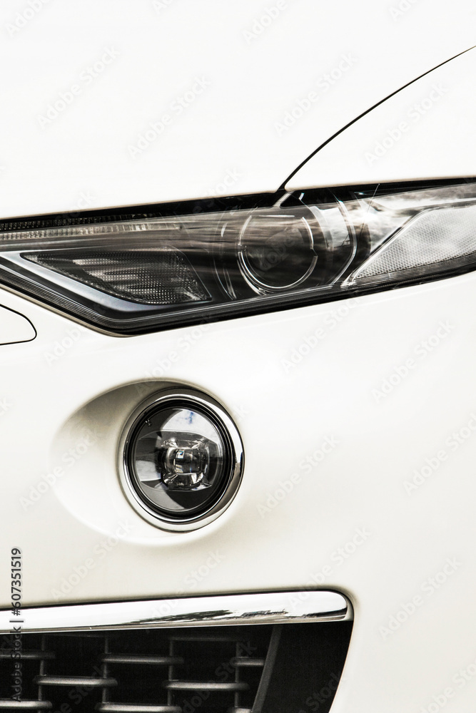 Car headlights. Luxury Headlights. Part of a white car close up. Bumper