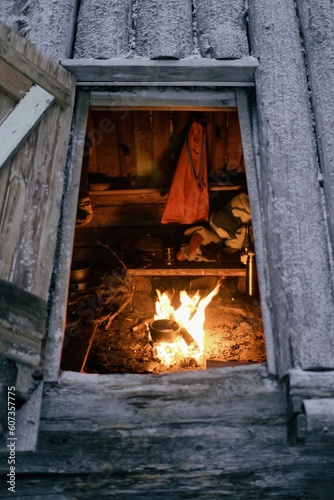 Vertical shot of a burning bonfire with cooking food in a wooden hut