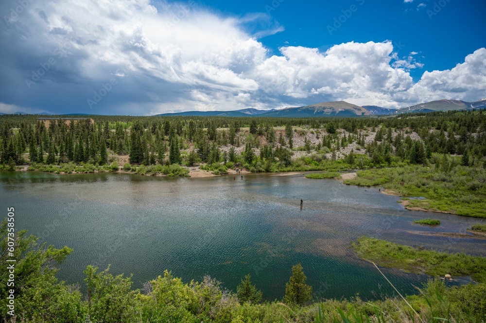 View of a lake and a green landscape under the blue sky with clouds in Colorado