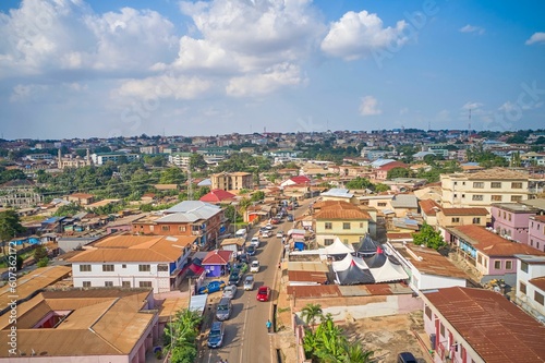 Fototapeta Naklejka Na Ścianę i Meble -  Aerial view of a small village filled with buildings and a road with cars in Kumasi, Ghana