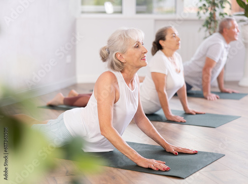 Elderly women practicing yoga in virabhadrasana pose in the gym