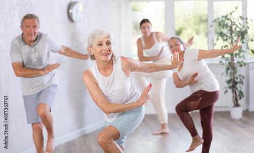 Group of happy mature sports women and man in activewear exercising dynamic dancing movemens in modern gym studio